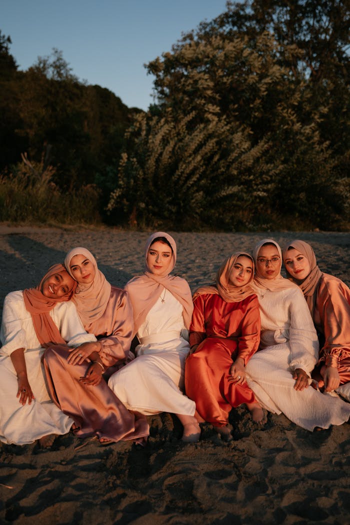 Beautiful Women Wearing Traditional Clothes while Sitting on the Beach Sand